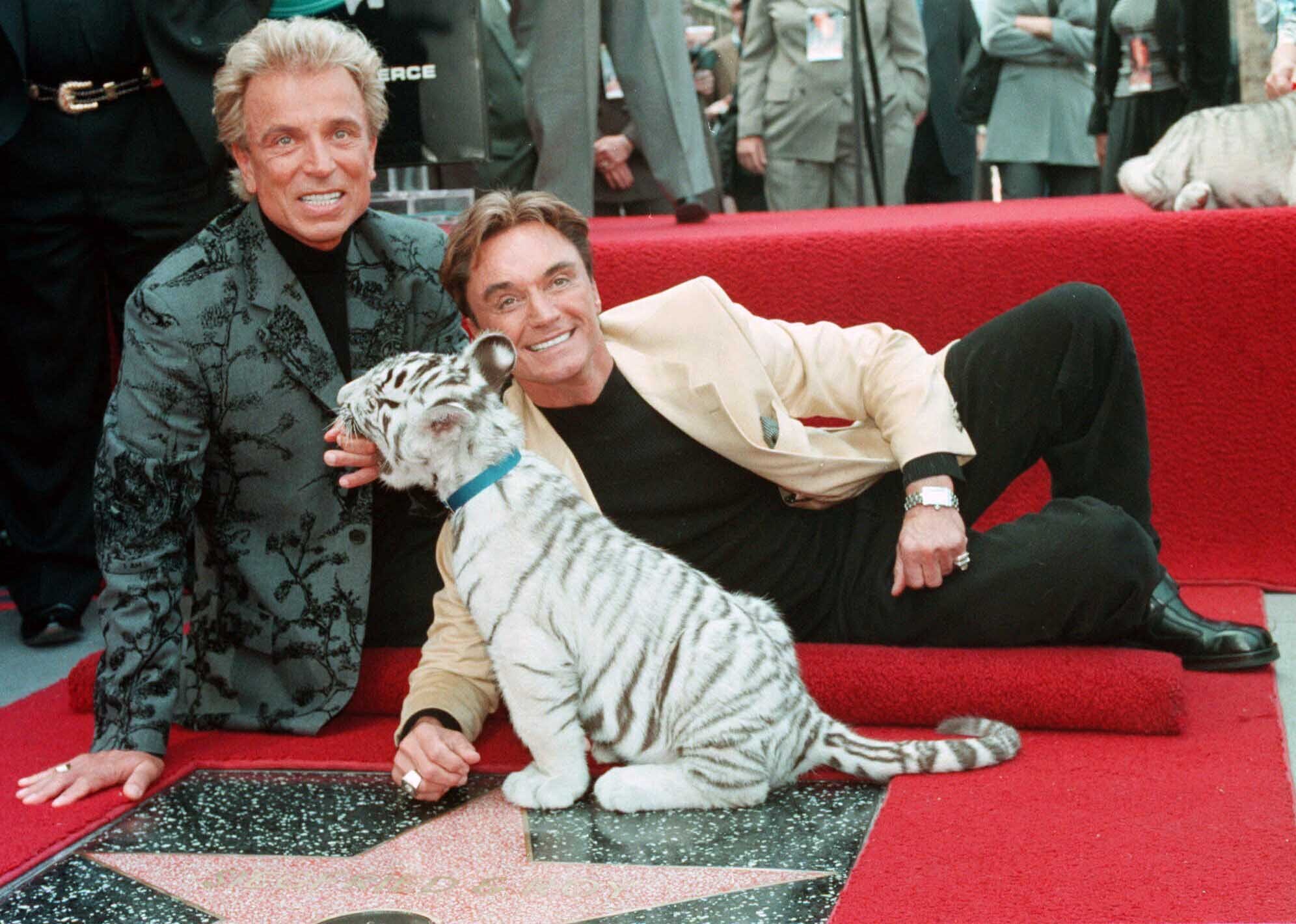 Illusionists Siegfried Fischbacher, left and Roy Uwe Ludwig Horn pose for photographers with a white tiger cub after they unveiled their star on the Hollywood Walk of Fame in Los Angeles, Calif., on Sept. 23, 1994.